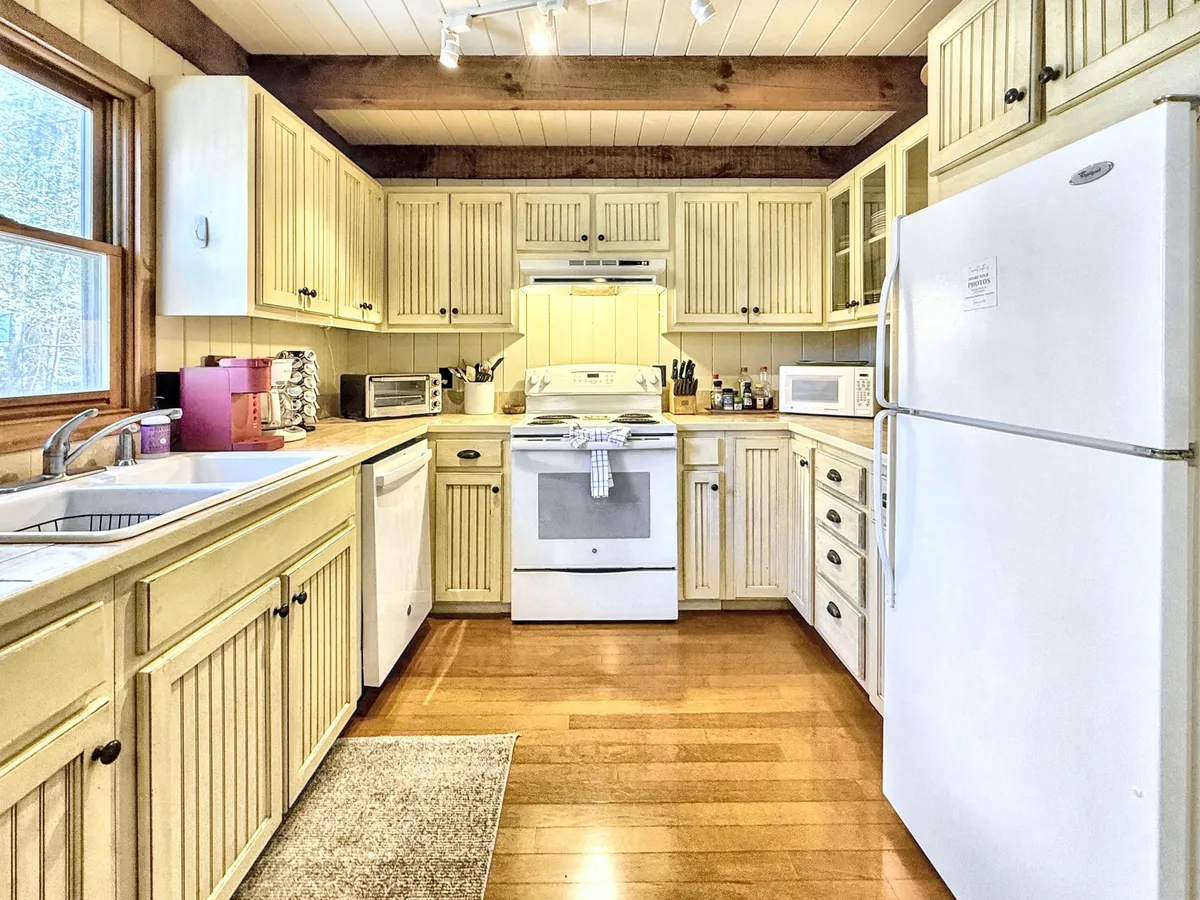 A warm interior shot displays wooden cabinetry, modern kitchen appliances, a spacious sink area, and generous counter space, all inviting for cooking, baking, and spending time together.